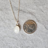 faceted white moonstone pendant beside a quarter