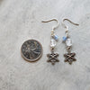 snowflake charm clear quartz dangle earrings beside a quarter