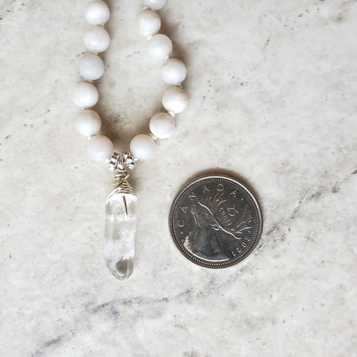 Silk knotted white crazy lace agate with crystal point beside a quarter