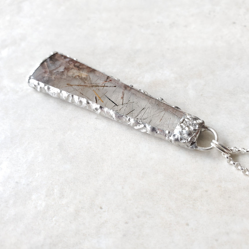 Silver pendant with a textured design on a white background