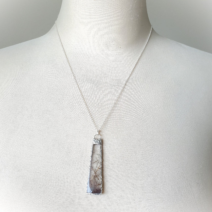 Necklace with a pendant on a mannequin against a neutral background