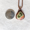 Freeform Imperial Jasper copper metalsmith pendant beside a quarter