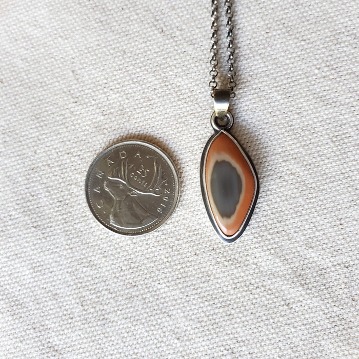 Freeform Imperial Jasper silversmith necklace beside a quarter