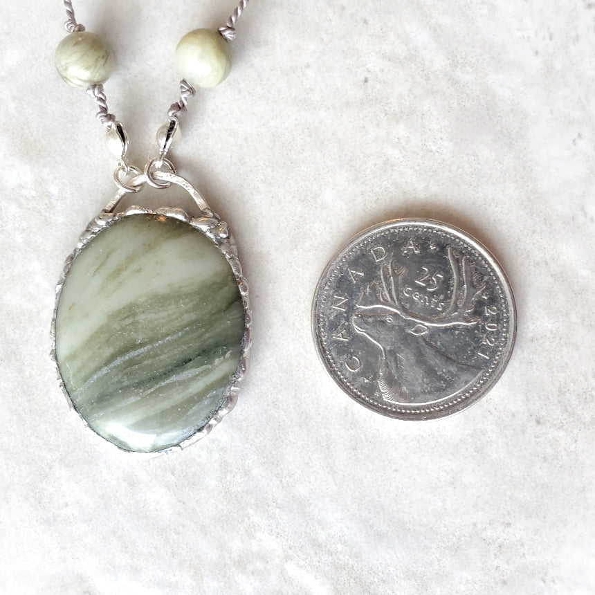Serpentine and Green Line Quartz knotted necklace beside a quarter