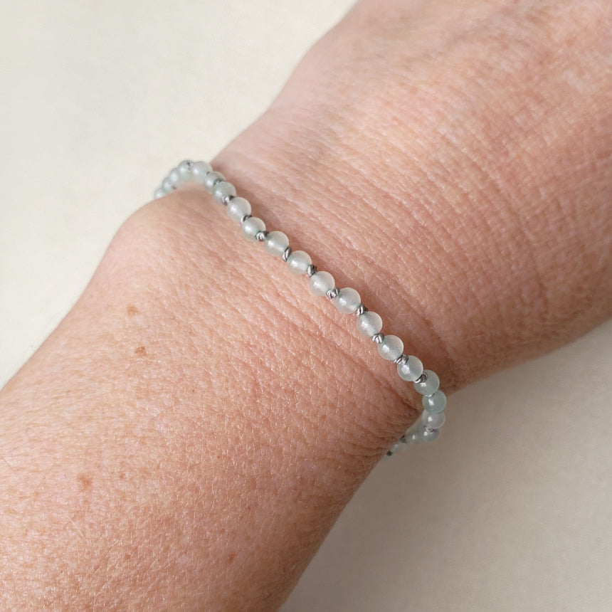 Close-up of a wrist wearing a beaded Green Aventurine bracelet on a plain background
