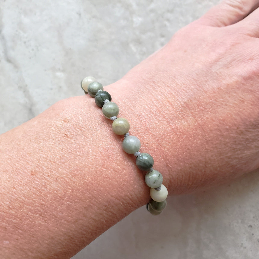 Beaded gemstone bracelet on a wrist with a neutral background