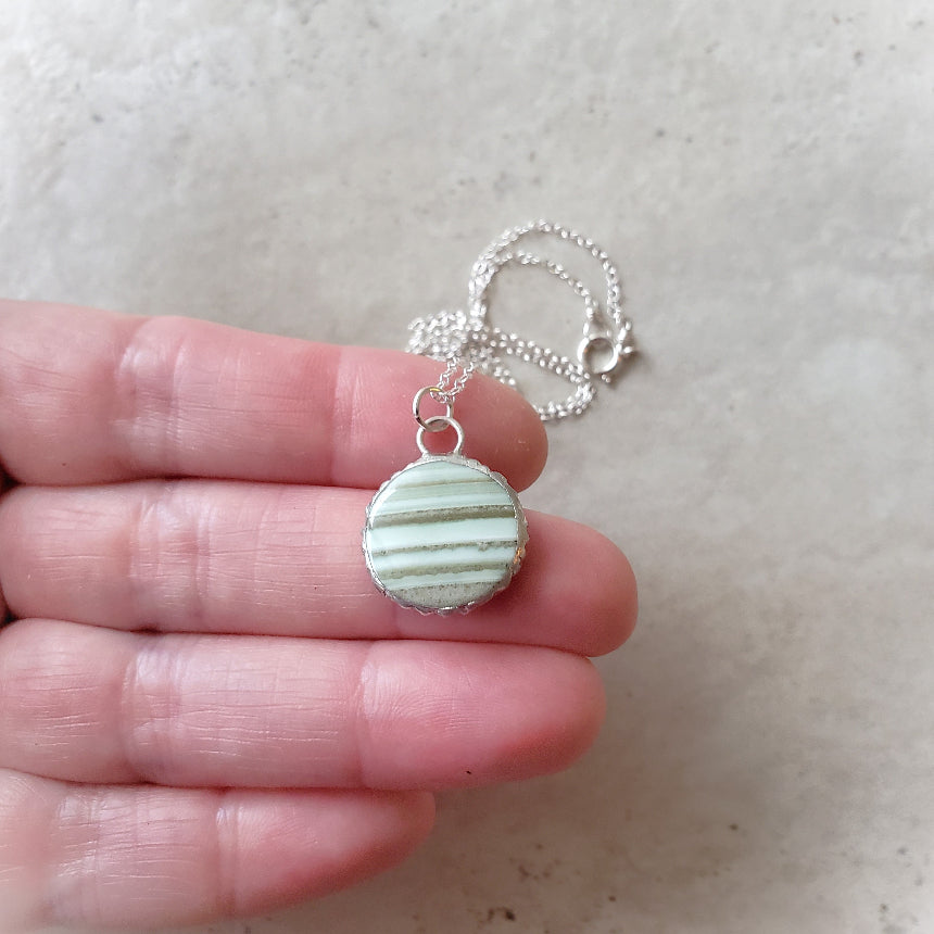 Green Saturn Chalcedony Round pendant necklace in hand