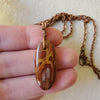 Noreena Jasper oval pendant copper necklace in hand