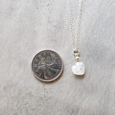 moonstone heart pendant beside a quarter