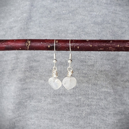 Moonstone heart earrings hanging on a branch