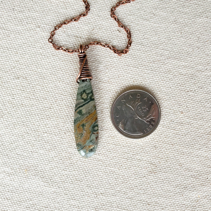 Teardrop Ocean Jasper copper pendant beside a quarter