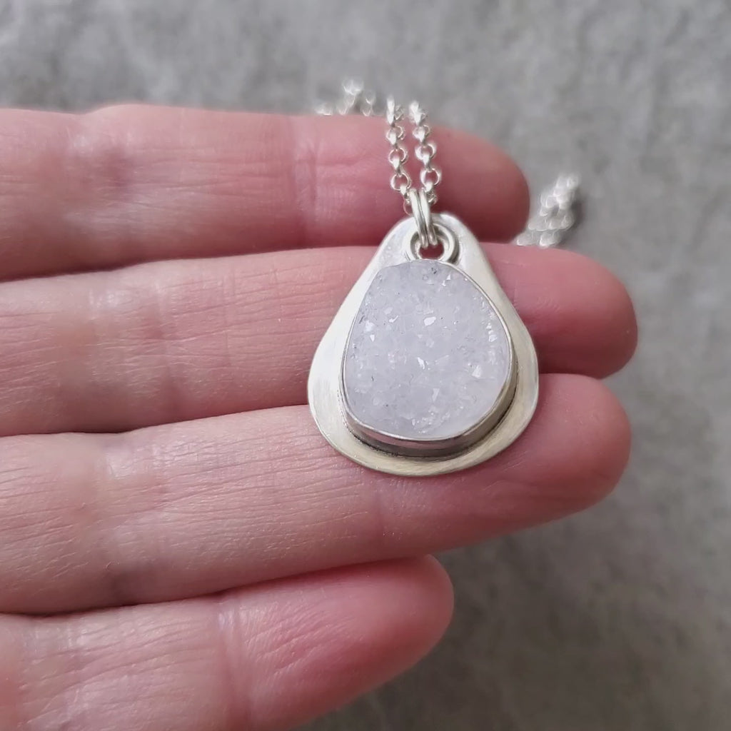 video of White druzy agate silversmith pendant in hand
