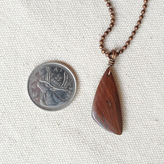 red tiger eye pendant beside a quarter