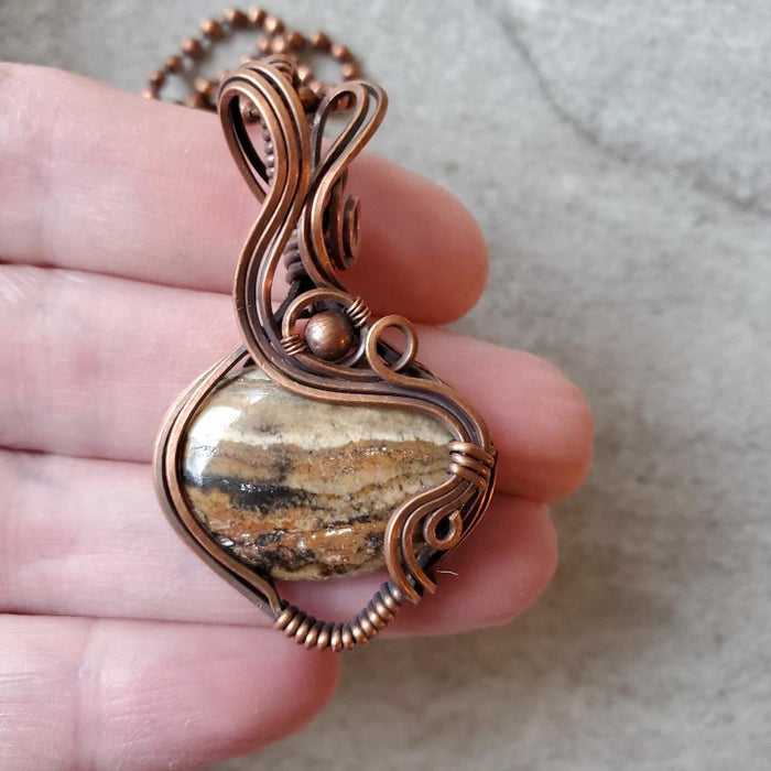 Aragonite wire wrap pendant in hand