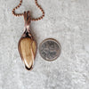 Aragonite wire wrap pendant beside a quarter