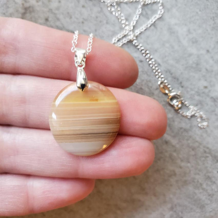 Banded Agate round pendant necklace in hand