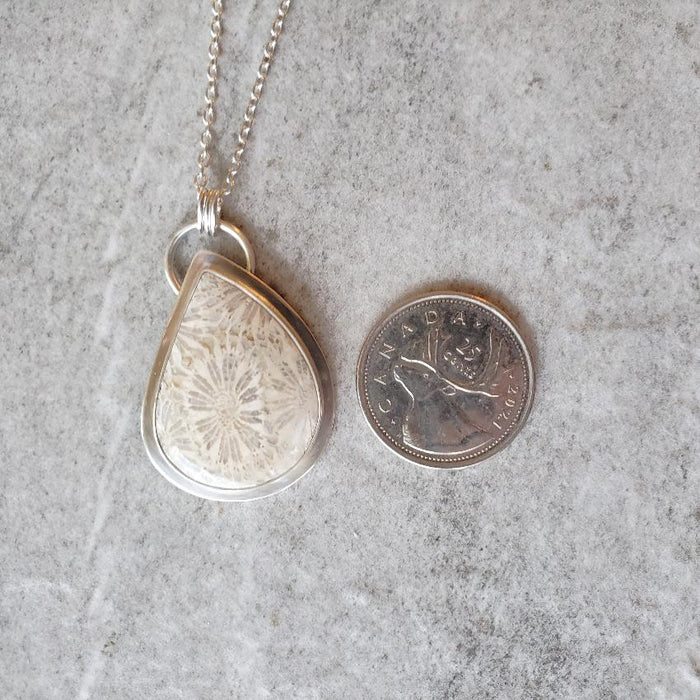fossil coral freeform silversmith pendant beside a quarter