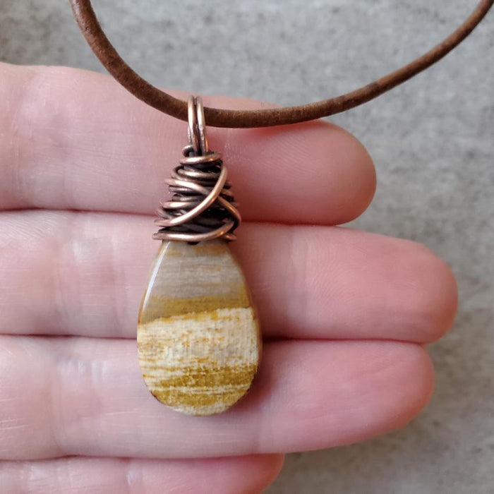 Petrified wood leather necklace in hand