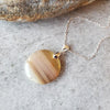 Banded Agate round pendant necklace on tile 