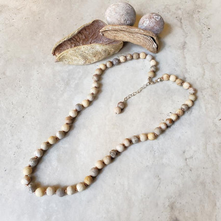 Frosted 6mm Fossil Coral knotted necklace on tile