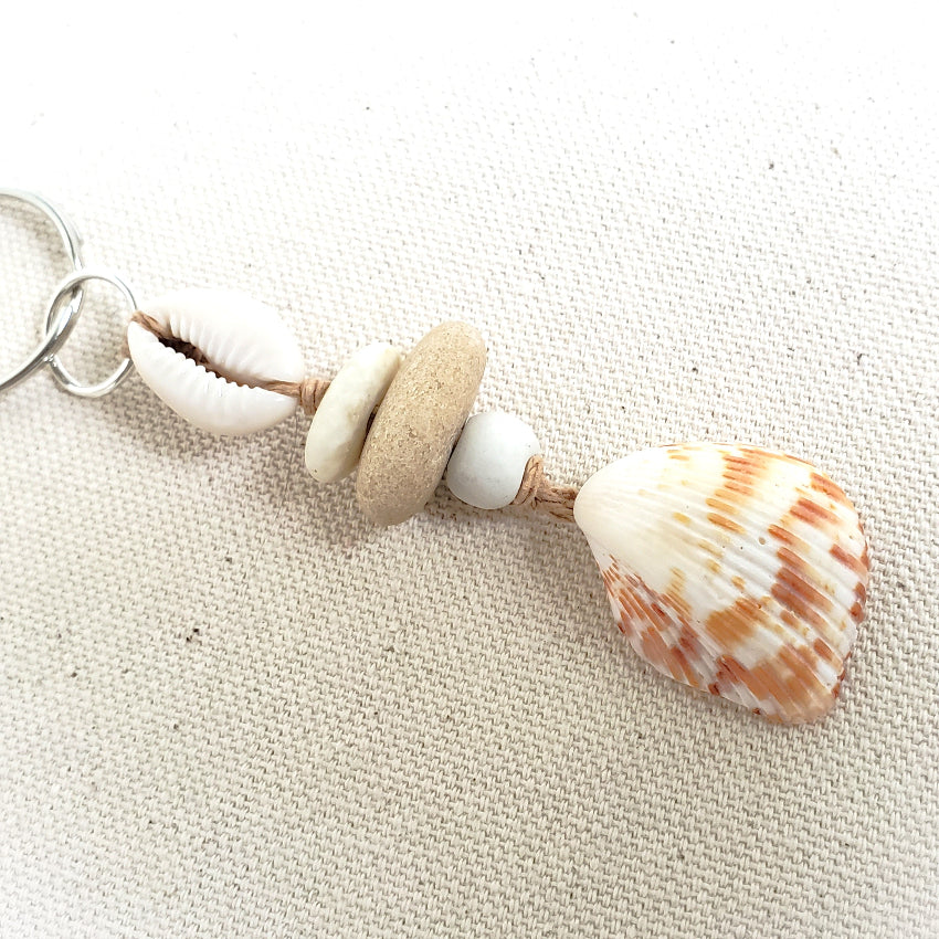 Keychain with seashells and beads on a textured beige surface