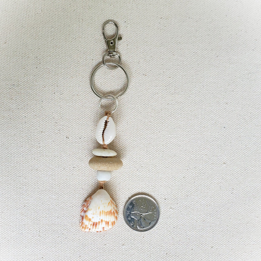 Keychain with seashells and a coin on a beige fabric background