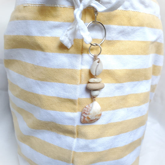Yellow and white striped bag with a keychain featuring seashells on a white background