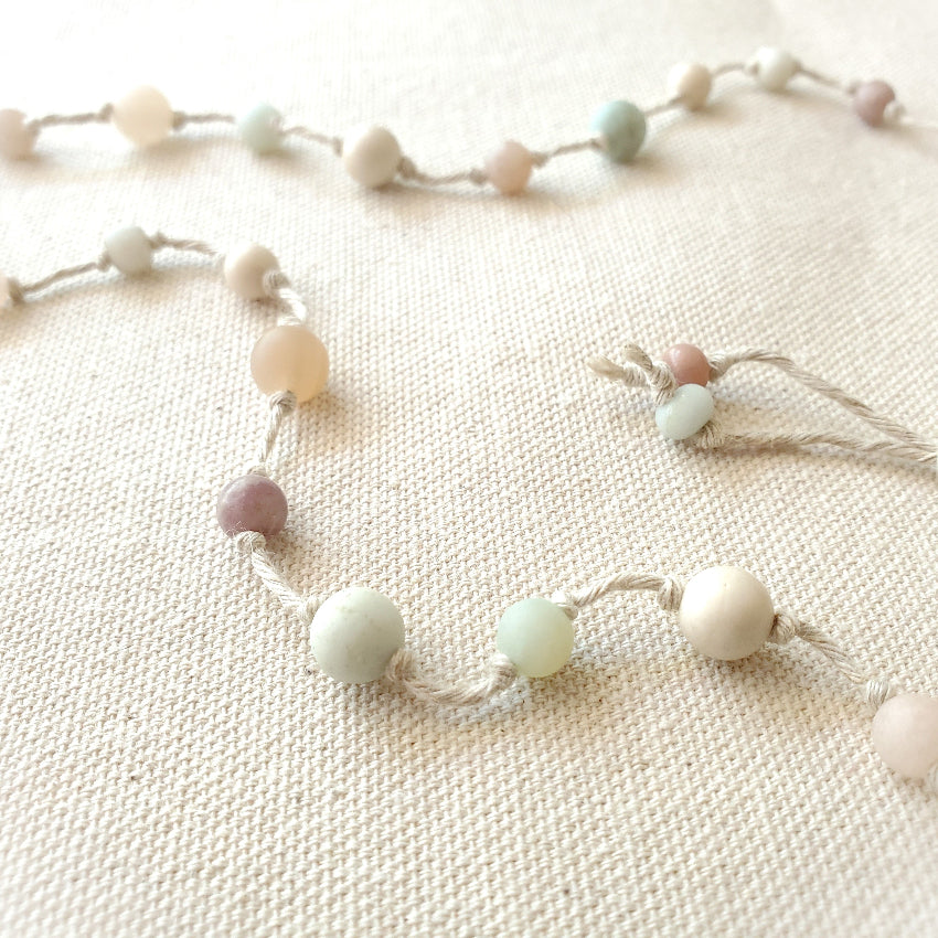 Necklace with pastel-colored beads on a textured beige surface