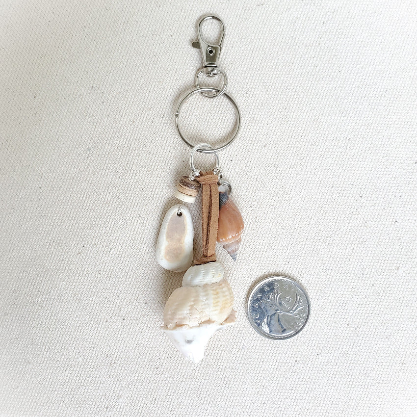 Keychain with seashells and a coin on a white background