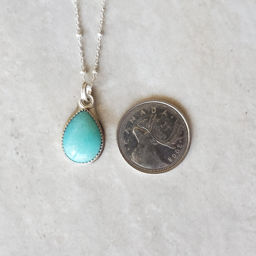 Amazonite teardrop silversmith necklace beside a quarter