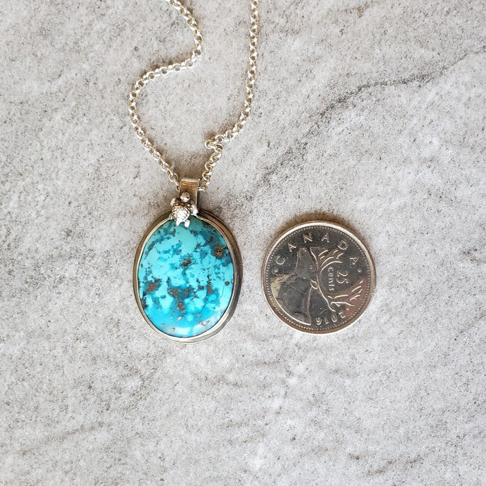 Morenci turquoise bezel set pendant beside a quarter