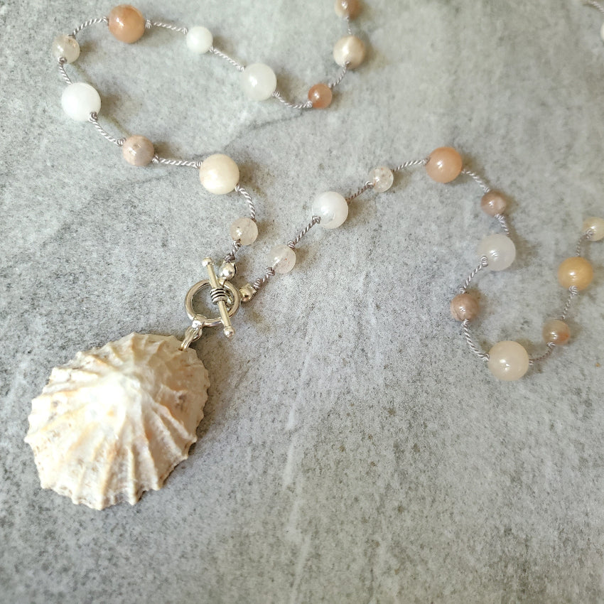 Necklace with shell pendant on a textured surface