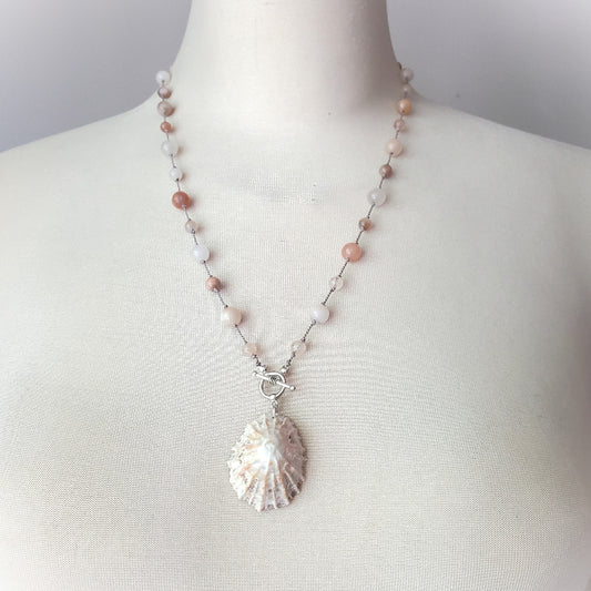 Necklace with shell pendant on a mannequin against a neutral background