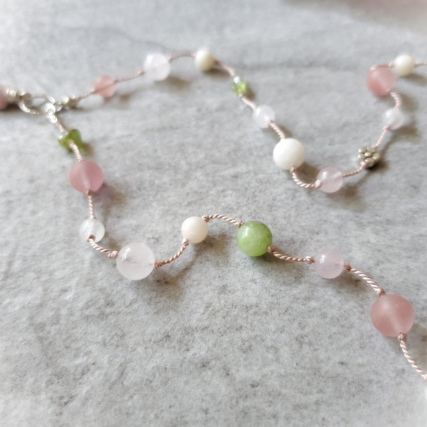 Necklace with pink and green beads on a gray surface