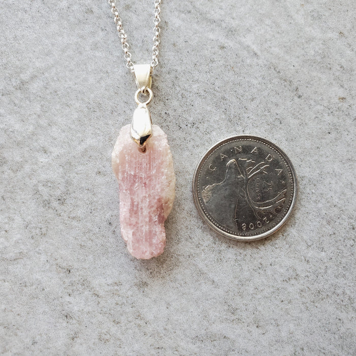 Pink Tourmaline nugget pendant necklace beside a quarter