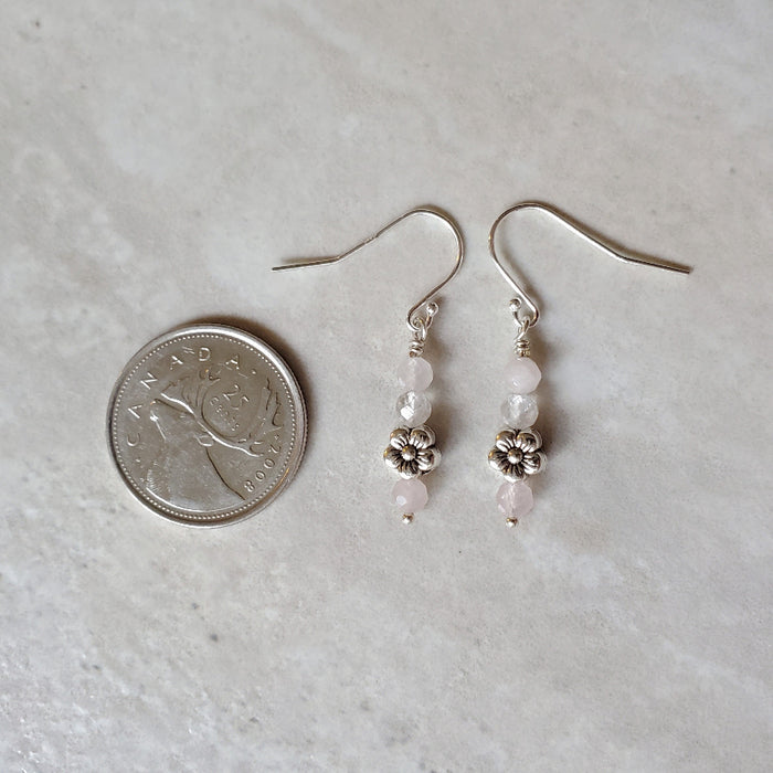 Faceted Rose Quartz earrings with flower accent beside a quarter