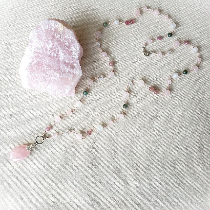 Necklace with pink pendant and beads on a light fabric background