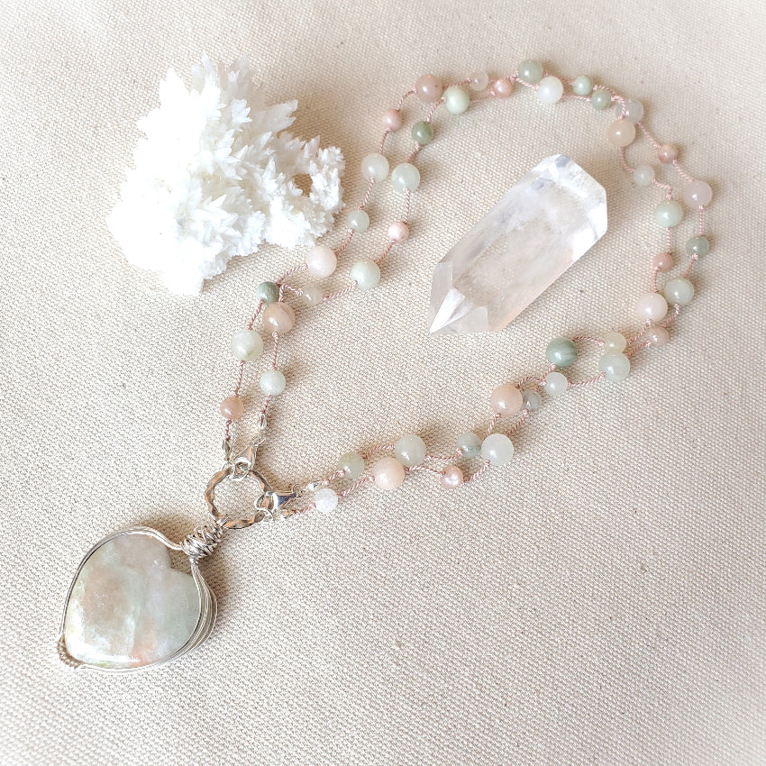 Necklace with a heart-shaped pendant and crystal on a beige fabric background