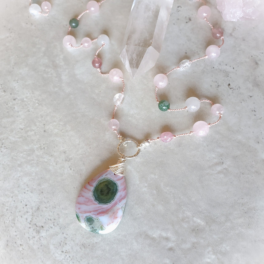 Pink and green gemstone knotted necklace on tile