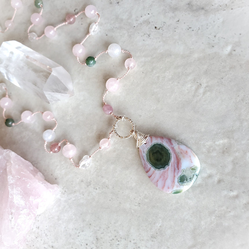 Pink and green gemstone knotted necklace on tile