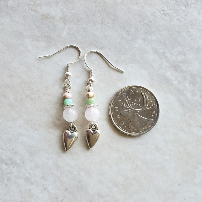 Rose Quartz heart earrings beside a quarter