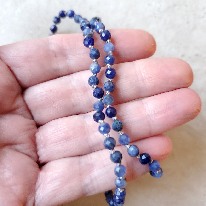 Faceted Sodalite necklace held in a hand against a neutral background