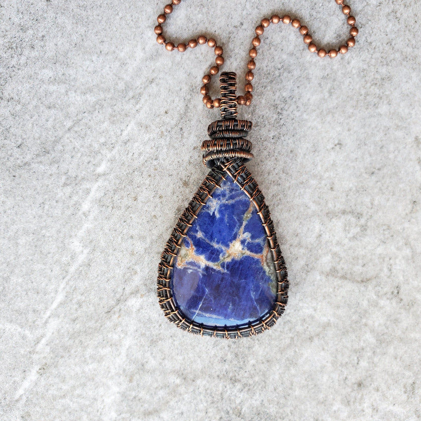 Sodalite copper wire wrap pendant on tile