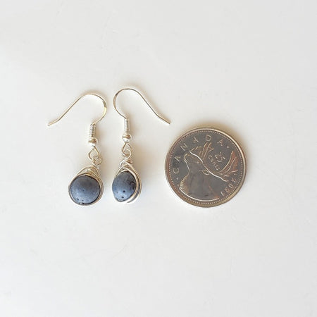 Blue fossil coral herringbone wrapped earrings beside a quarter