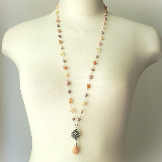 Necklace with multicolored beads and a decorative pendant on a mannequin.