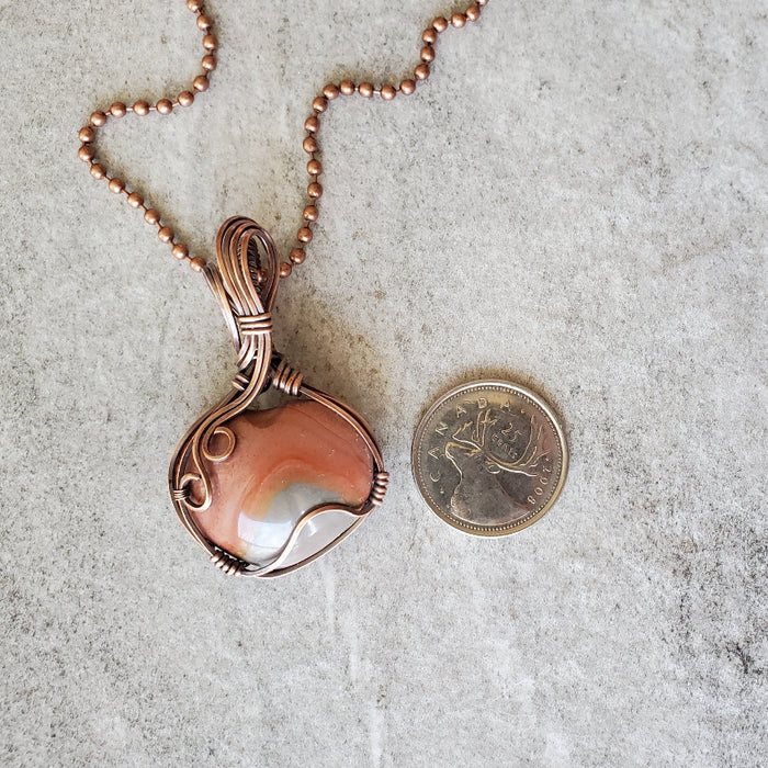 Polychrome Jasper wire wrapped heart pendant beside a quarter