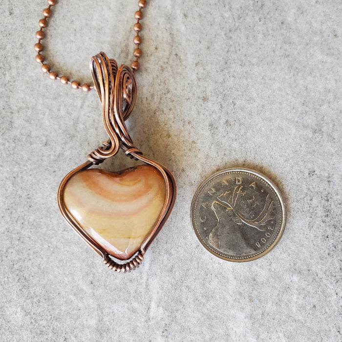 Polychrome Jasper wire wrap pendant necklace beside a quarter