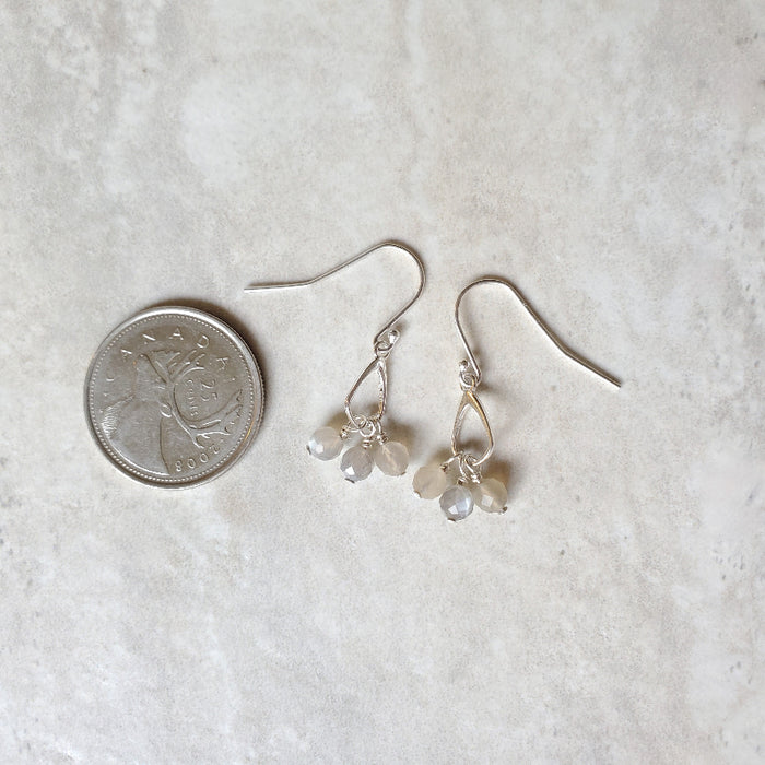 Faceted Grey Moonstone sterling silver dangle earrings beside a quarter