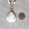 Howlite long knotted necklace beside a quarter