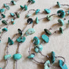 Hand knotted turquoise chips on silk cord laying on linen